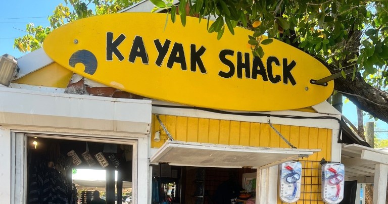 Yellow sign reads 'Kayak Shack' on a small wooden building.