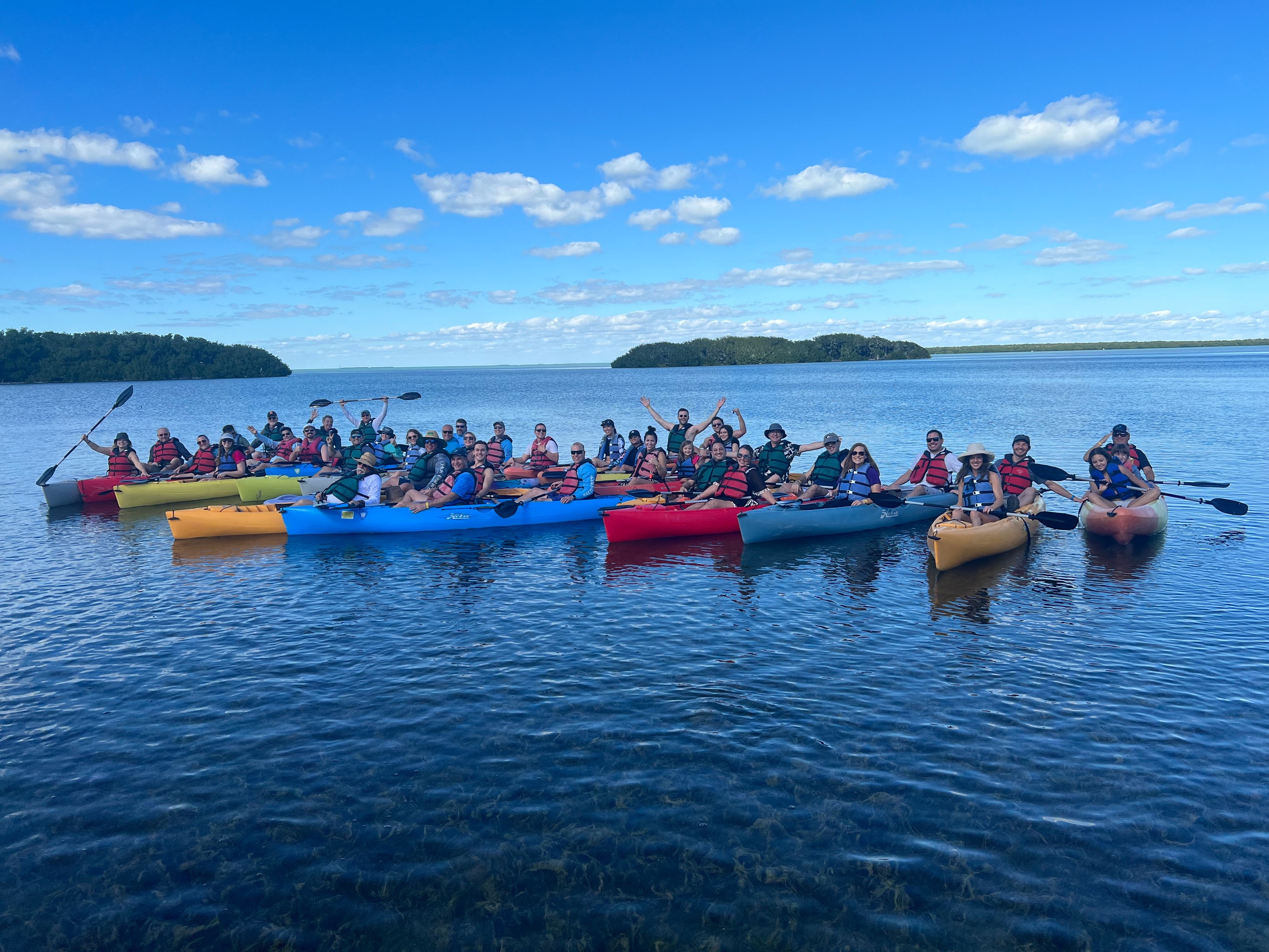 Group of kayakers on a lake under a clear blue sky.