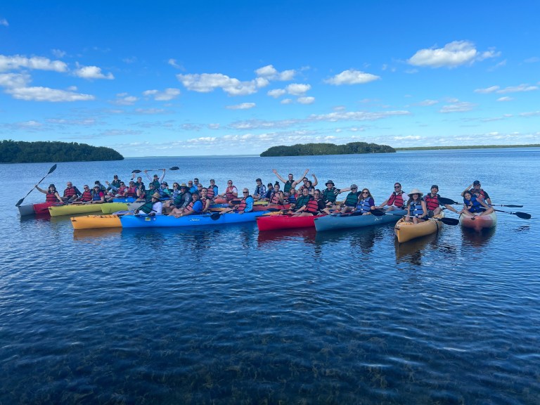 Group of kayakers on a lake under a clear blue sky.