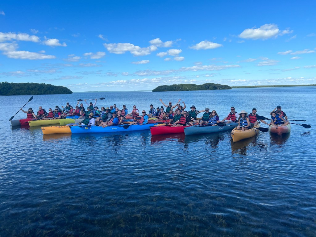 Group of kayakers on a lake under a clear blue sky.